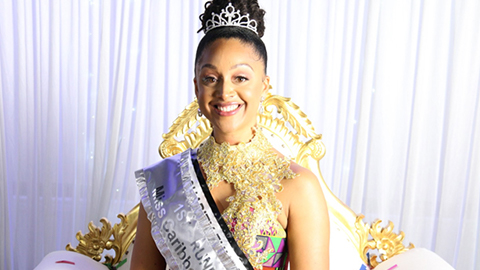 Ashlea Smith is pictured smiling wearing a tiara and a silver coloured sash. She is seated on a gold and white chair, taken against a white curtain backdrop. 